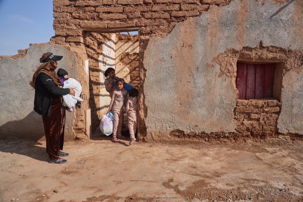 Una donna e alcuni bambini fanno ritorno alla loro casa, danneggiata sette anni fa da un’offensiva militare turca che li aveva costretti a fuggire, nella campagna di Ras al-Ayn(AP Photo/Baderkhan Ahmad)