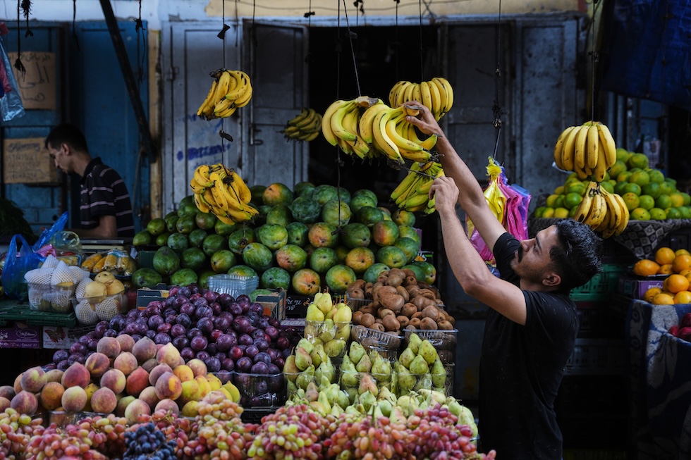 Un venditore sistema la frutta in un mercato nel campo profughi di al-Shati (AP Photo/Abdel Kareem Hana)