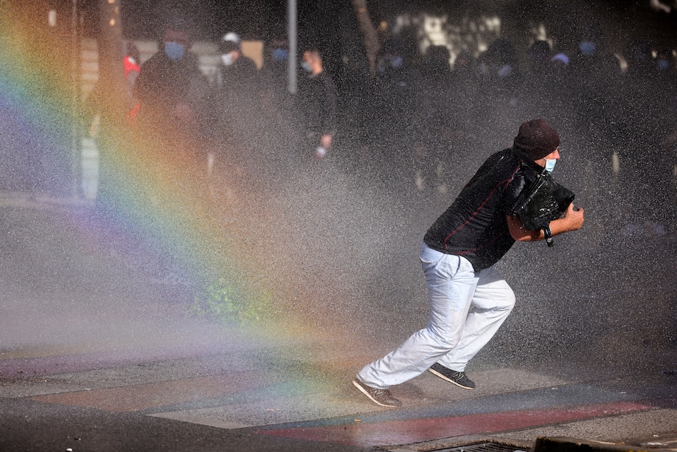 Un manifestante corre per evitare il getto d’acqua di un idrante della polizia durante una protesta organizzata dal movimento antigovernativo noto come "Flamingo” per chiedere le dimissioni del primo ministro Edi Rama (AP Photo/Hameraldi Agolli)