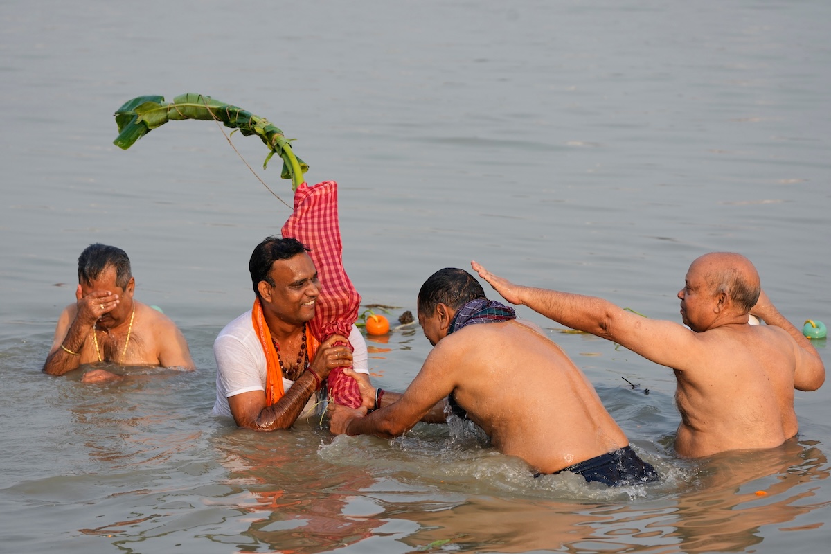 Alcuni uomini induisti si immergono nell'acqua del fiume Hughli insieme a un banano per la festa annuale Durga Puja(AP Photo/Bikas Das)