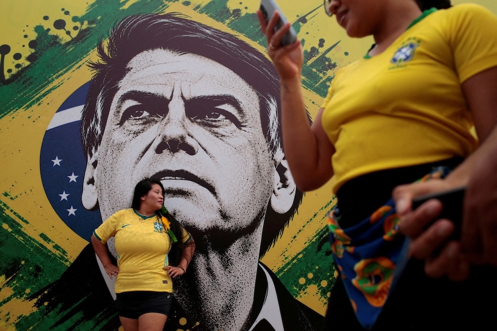 Una donna davanti a un murale dell'ex presidente brasiliano Jair Bolsonaro a un comizio del figlio, Flavio Bolsonaro, che ha vinto il primo turno delle elezioni presidenziali e secondo i sondaggi è in vantaggio per il ballottaggio del 25 ottobre (REUTERS/Suamy Beydoun)