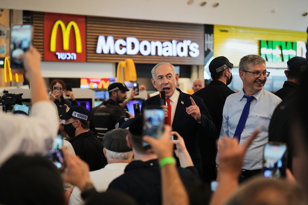 Il primo ministro israeliano Benjamin Netanyahu parla con i suoi sostenitori davanti a un McDonald's in un centro commerciale, durante la campagna elettorale in vista delle elezioni politiche. La foto è stata scattata ieri. (AP Photo/Ariel Schalit)