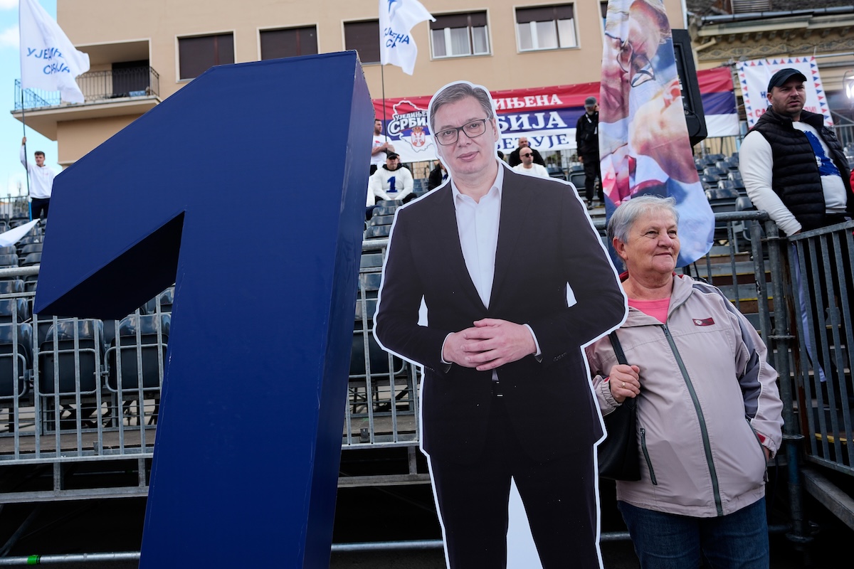 Una sostenitrice di Vucic in posa con un suo ritratto a un comizio del suo partito, il 16 ottobre 2026, a Novi Sad (AP/Darko Vojinovic)