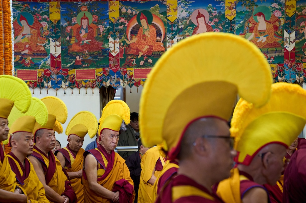 Monaci buddisti tibetani in esilio, con indosso copricapo cerimoniali gialli, attendono l’arrivo del Dalai Lama al tempio di Tsuglakhang (AP Photo/Ashwini Bhatia)
