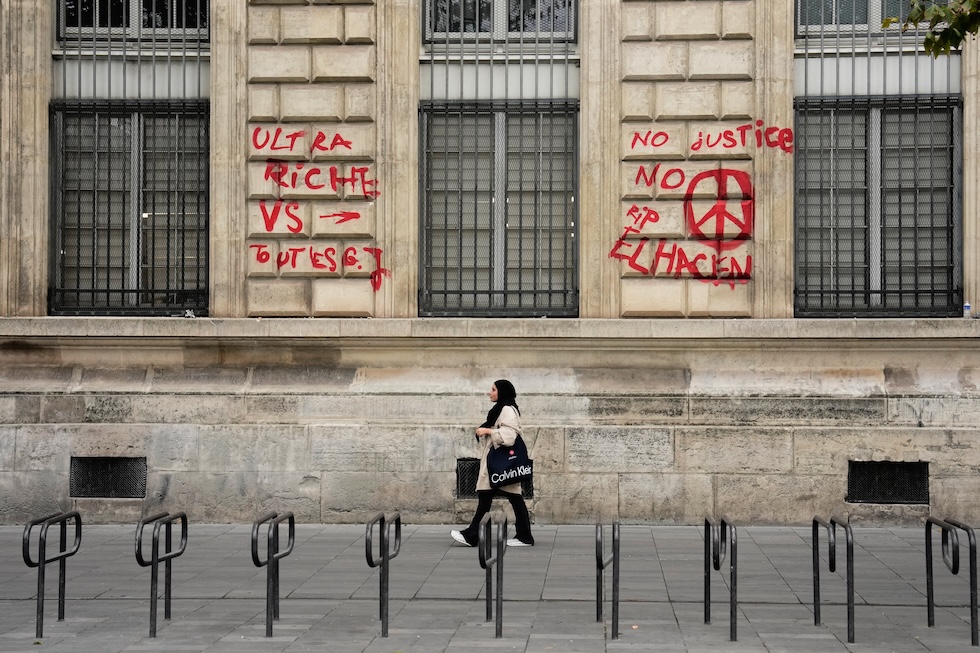 Una donna passa davanti a un edificio con delle scritte sui muri (AP Photo/Teresa Suarez)
