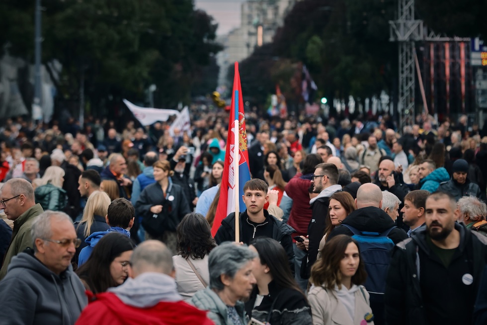Un giovane tiene una bandiera serba durante una grande manifestazione organizzata dal movimento degli studenti, che ha presentato una propria lista per partecipare alle elezioni per il parlamento in programma domenica (AP Photo/Marko Drobnjakovic)