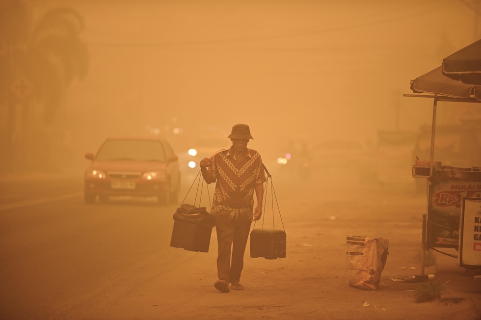 Un venditore ambulante cammina nella foschia causata dagli incendi. (AP Photo/Yulianus Stefan Lundju)