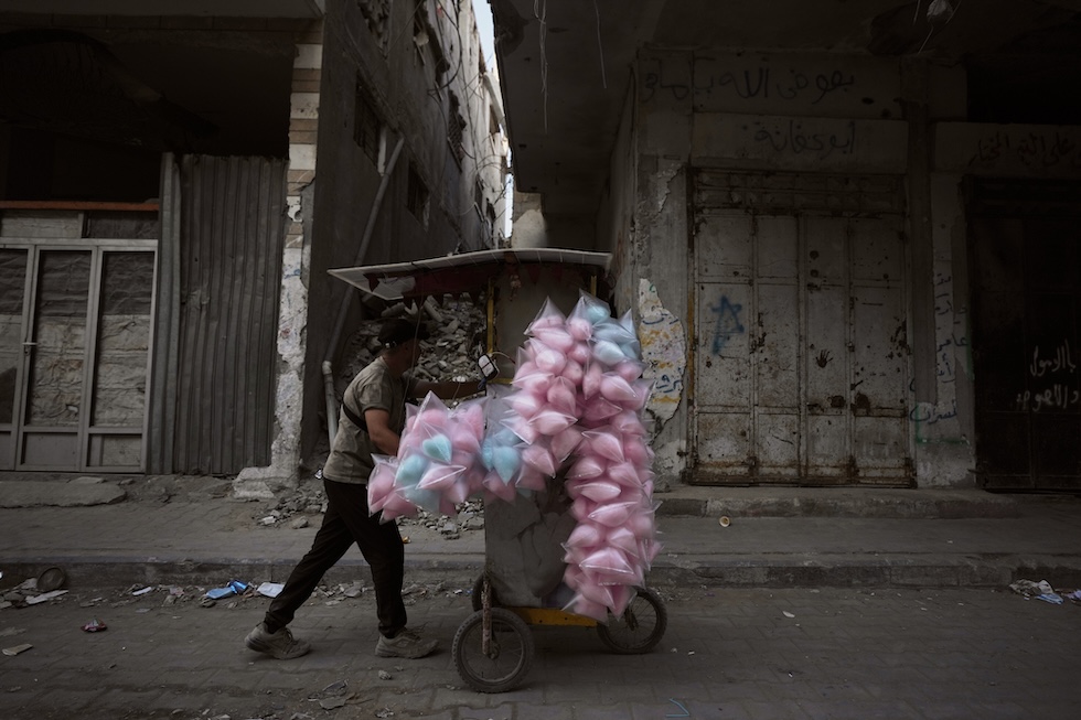 Un venditore palestinese di zucchero filato spinge il suo carretto per le strade di Gaza (AP Photo/Jehad Alshrafi)