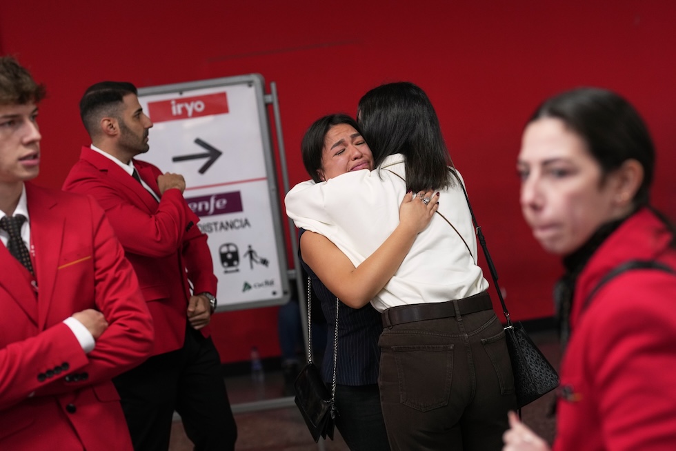 Due donne si abbracciano alla stazione di Atocha, dopo un minuto di silenzio dei dipendenti della compagnia ferroviaria Iryo in memoria delle persone morte nel grave incidente ferroviario di ieri (AP Photo/Bernat Armangue)