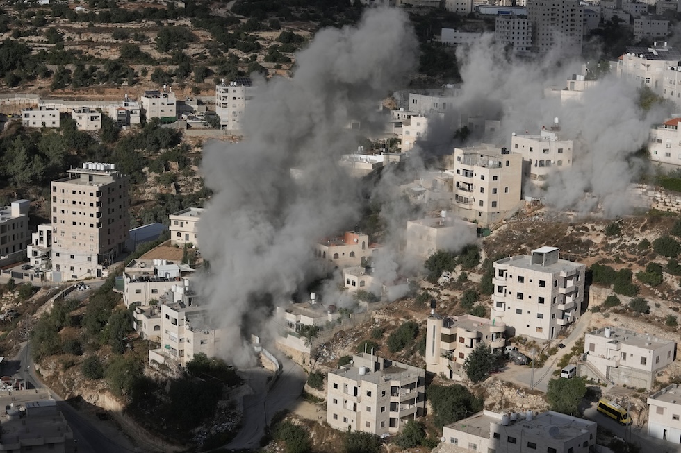 Colonne di fumo e polvere si alzano da due abitazioni demolite con gli esplosivi dall’esercito israeliano (AP Photo/Mahmoud Illean)