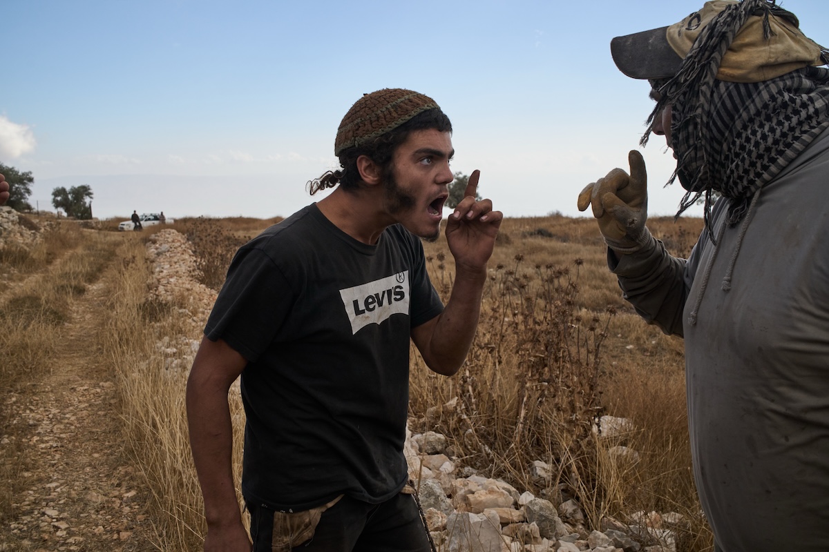 Un colono israeliano urla a un uomo palestinese mentre cerca di impedire agli abitanti locali di continuare la raccolta delle olive (AP Photo/Leo Correa)
